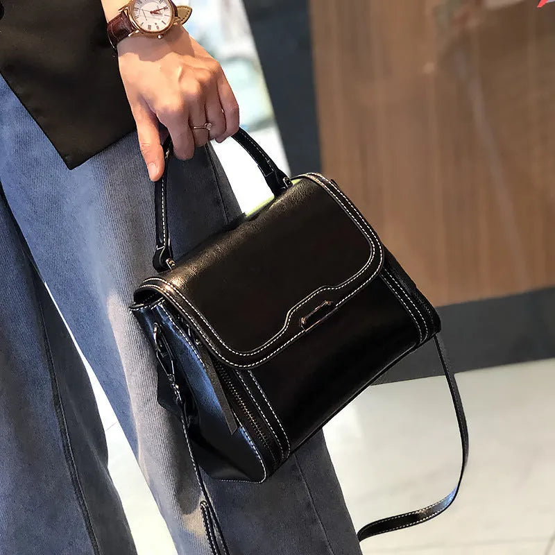 Women's brown genuine oil wax leather messenger bag with double strap and external pocket.