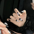 Black and pink heart-shaped press-on false nails with bow design, shown in mid-length cat's eye style.