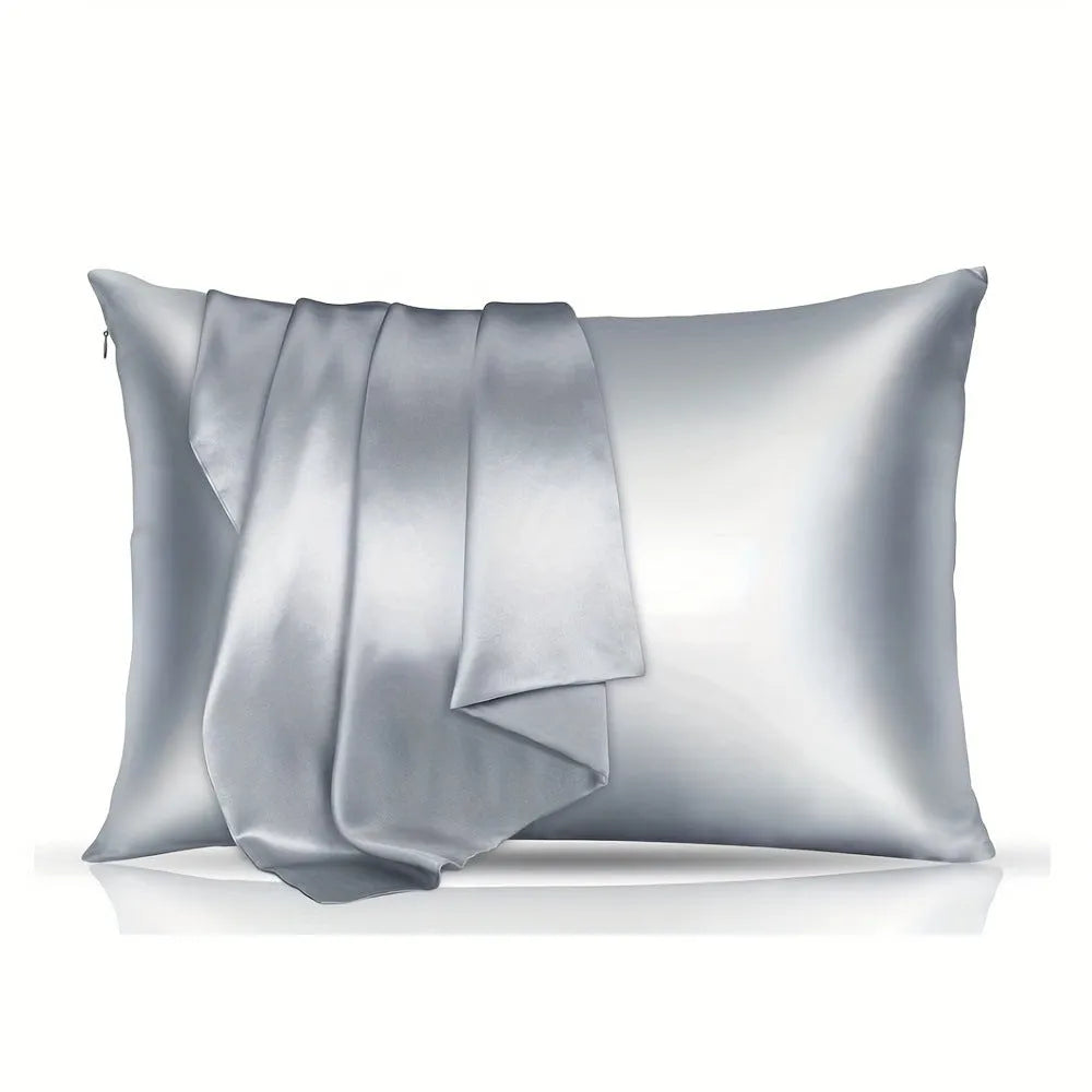 Pair of solid colour satin pillowcases in polyester fabric on a bed.