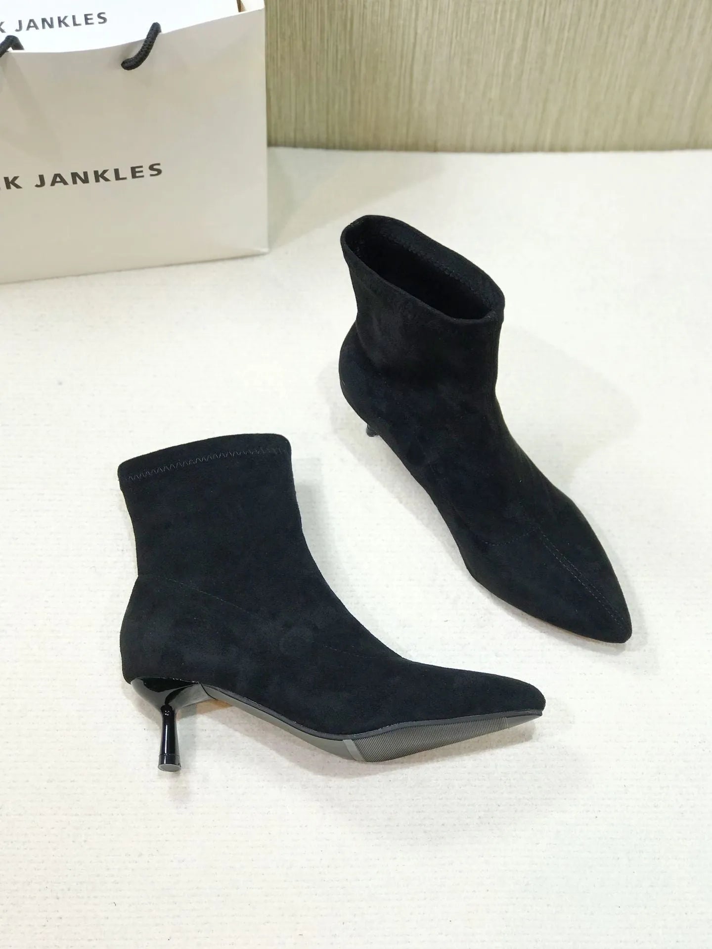 Black pointed toe ankle boots with a stiletto heel on a plain background.