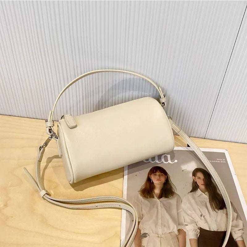 Soft vegetable-tanned leather crossbody phone bag in cylindrical shape with adjustable strap.