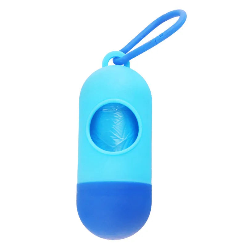 A small black plastic dog poop bag holder with a hook and Velcro strap, shown next to a roll of bags.