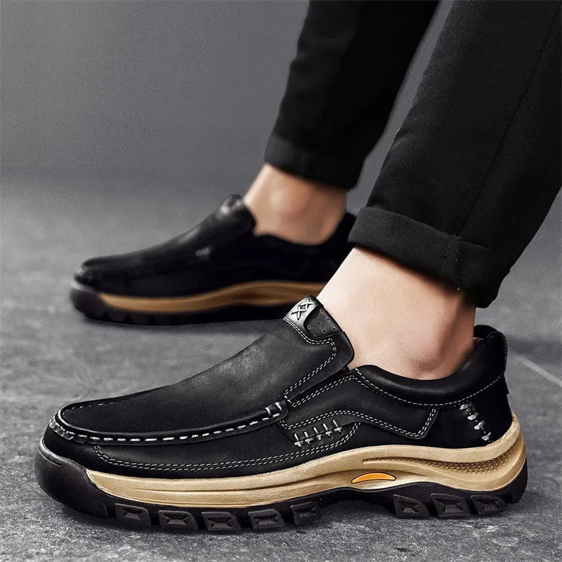 Men's black leather mountaineering shoes with thick rubber soles and round toe on a neutral background.