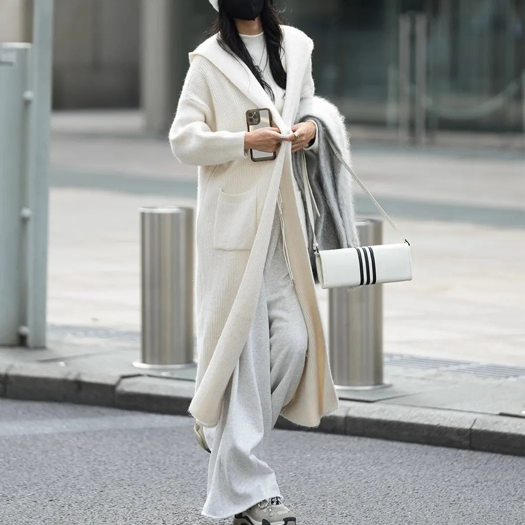 Long grey knitted women's cardigan trench coat with a hood and long sleeves.