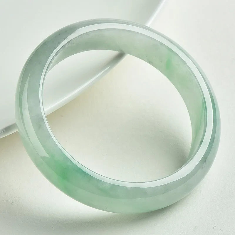 Light green polished jade bracelet in a natural style on a wrist.