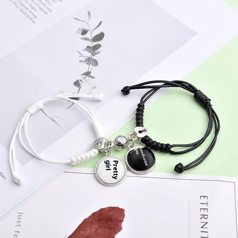 Pair of magnet couple bracelets with suction clasp on wrist, showing alloy designs like crown and love lock.