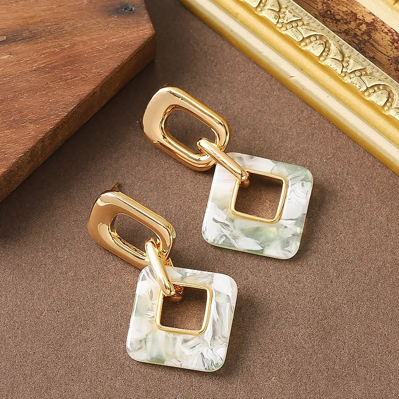 A pair of hollow geometric square copper earrings with a chamfered pattern design.