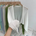 Thin loose linen blouse with hollow out lantern sleeves in apricot colour on a hanger.