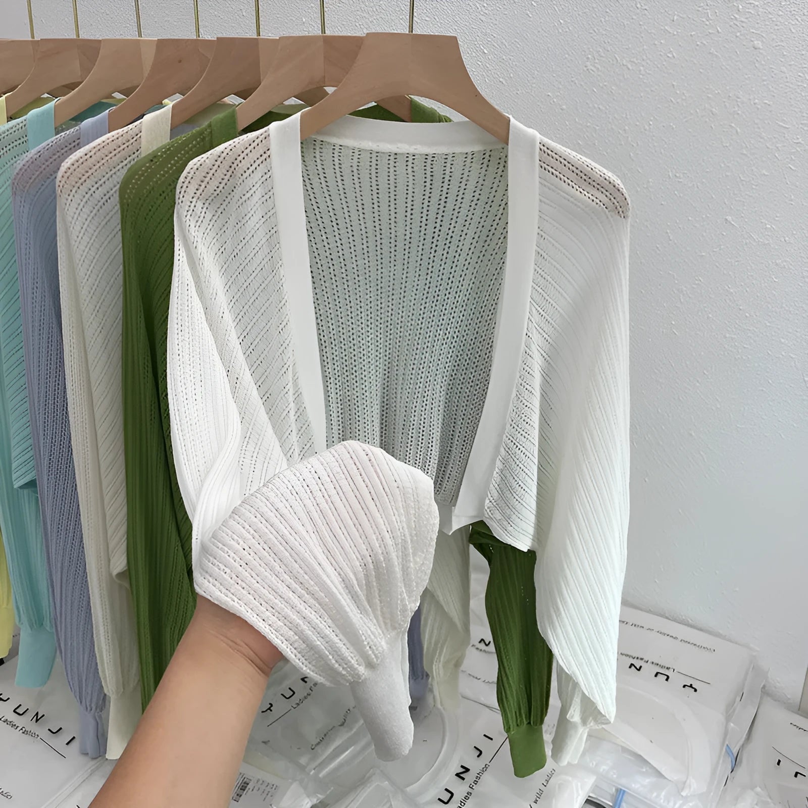Thin loose linen blouse with hollow out lantern sleeves in apricot colour on a hanger.