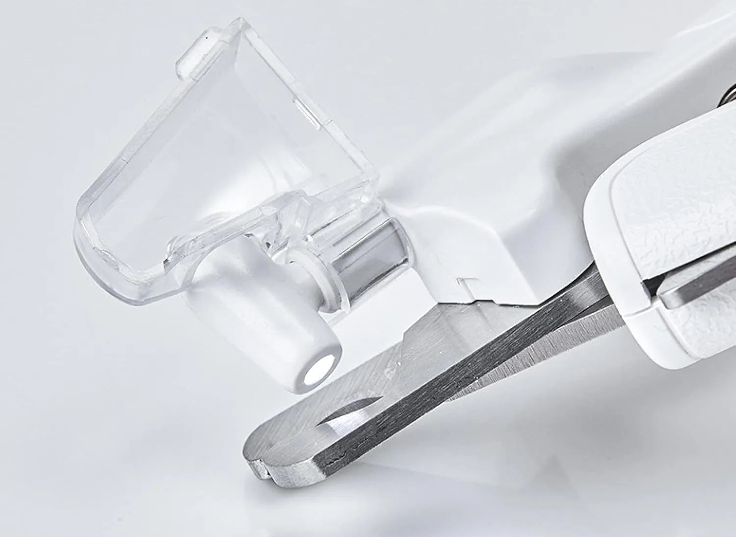 White pet nail clippers with LED light, open transparent splash guard, and separate nail file on a table