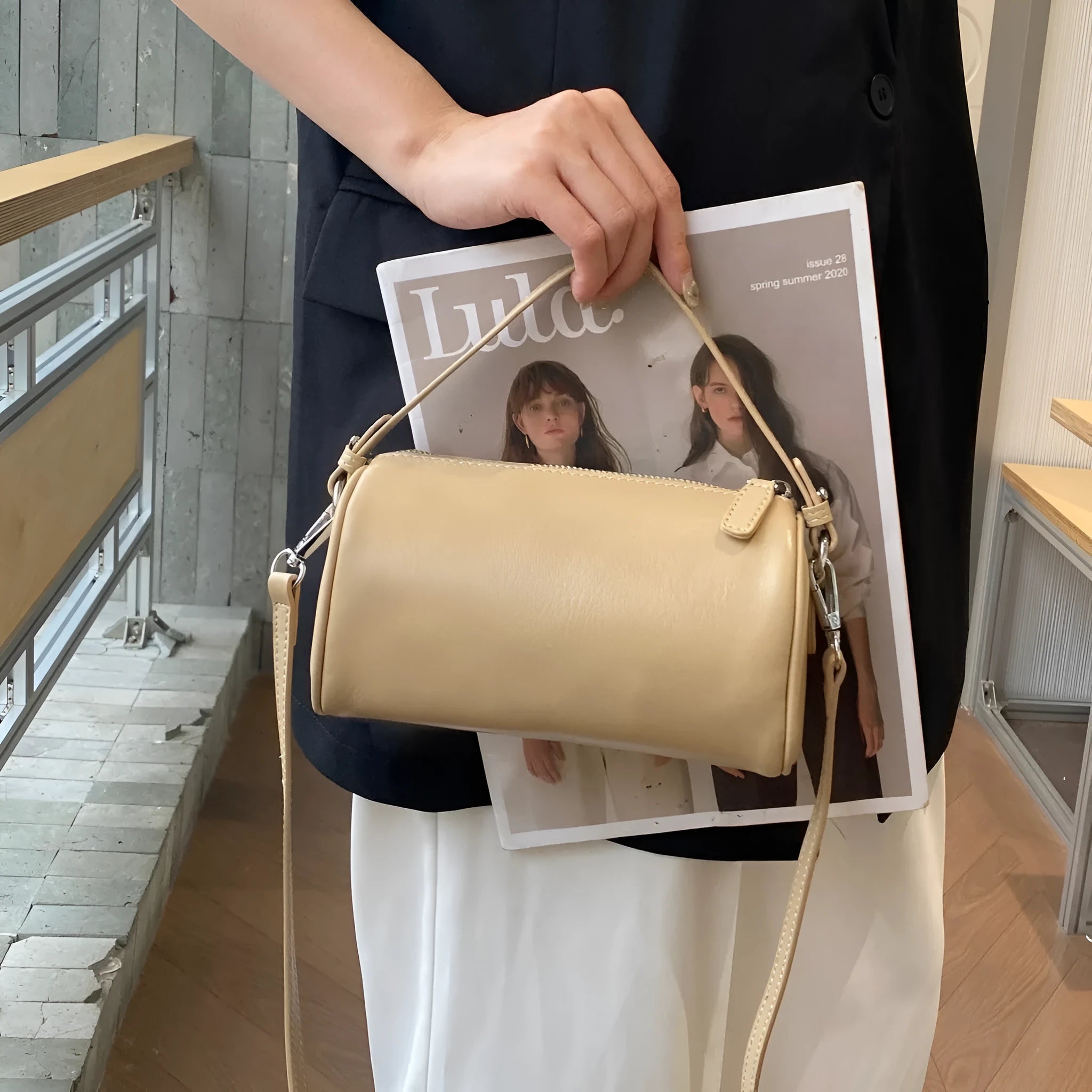 Soft vegetable-tanned leather crossbody phone bag in cylindrical shape with adjustable strap.