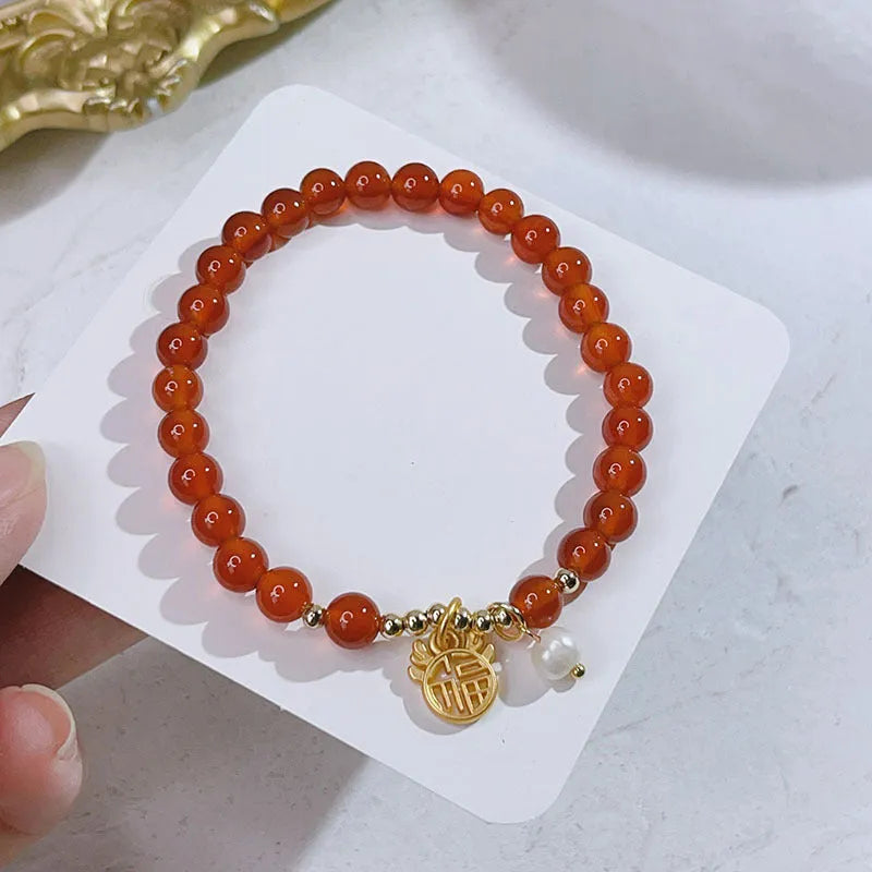 A red agate bracelet for women with Chinese style dragon and lucky bag motifs.