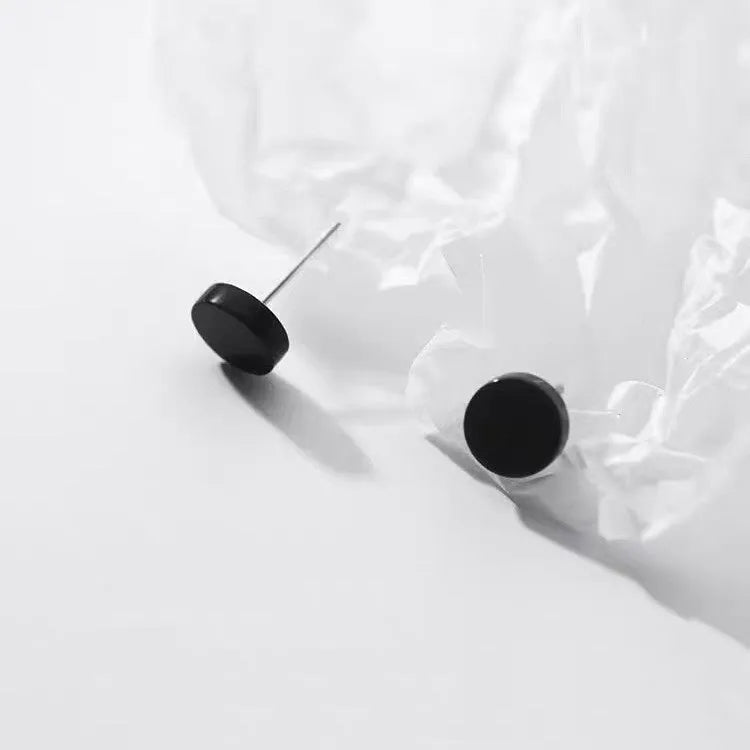 A pair of simple, round, flat-fronted S999 sterling silver ear bone studs on a plain background.
