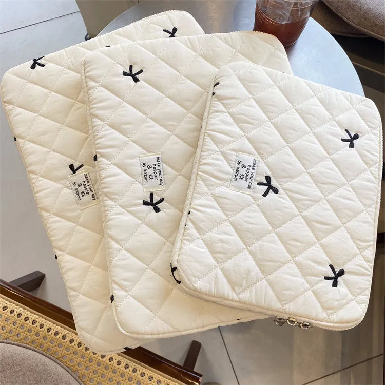 Cute white nylon laptop bag with a rhombus embroidered bow, shown next to a laptop.