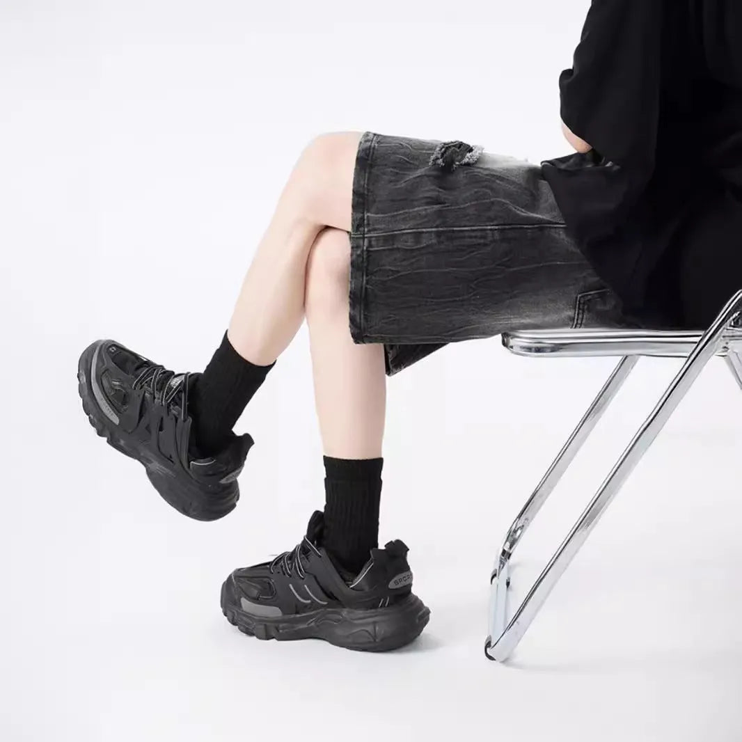 Man's loose-fit ripped denim shorts in washed black showing distressed details and retro styling