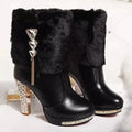 Women's black and white ankle boots with a chunky high heel on a solid colour background