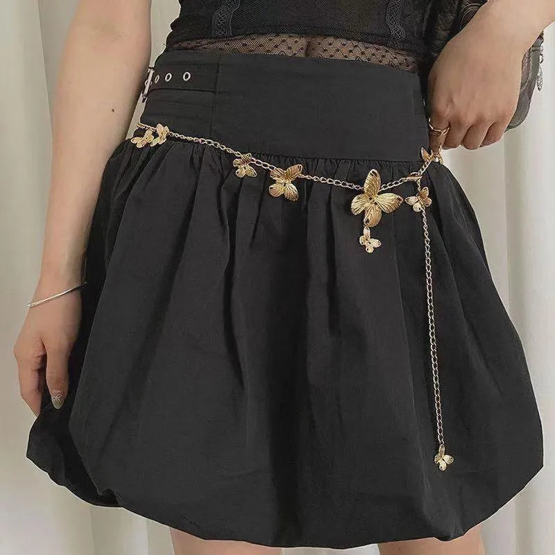 Gold and silver butterfly motif waist chain jewellery belt for women on a plain background.