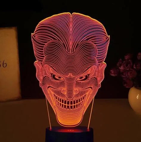 A clear acrylic 3D LED table lamp displaying gradient colours, standing on a square base with a USB cable and remote control.