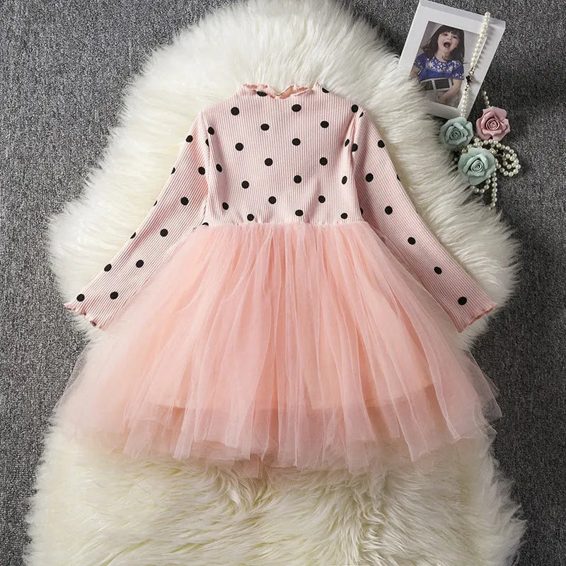A baby girl wearing a long sleeve black tutu and lace dress for a birthday party.