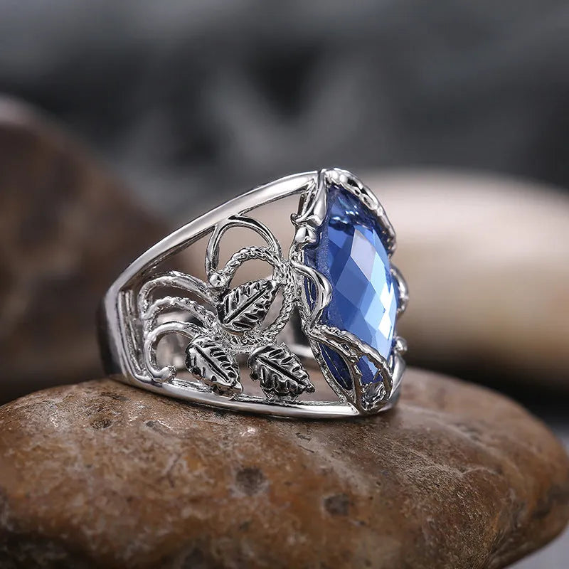 Close-up of a women's horse eye shaped blue crystal ring on a finger.