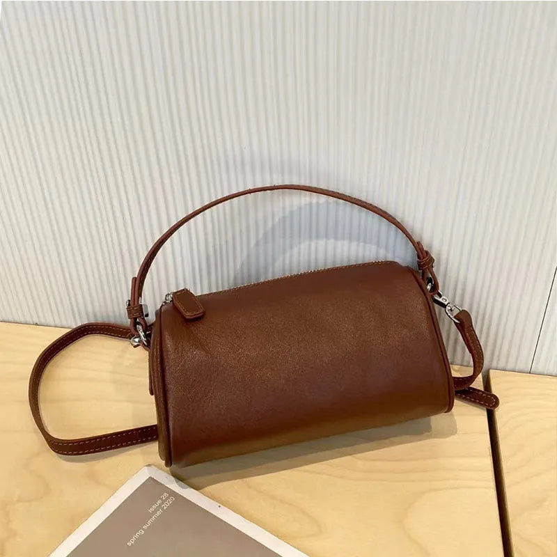 Soft vegetable-tanned leather crossbody phone bag in cylindrical shape with adjustable strap.