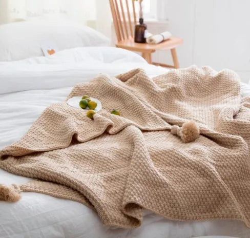 Nordic fringed knit ball acrylic blanket in beige colour on a sofa