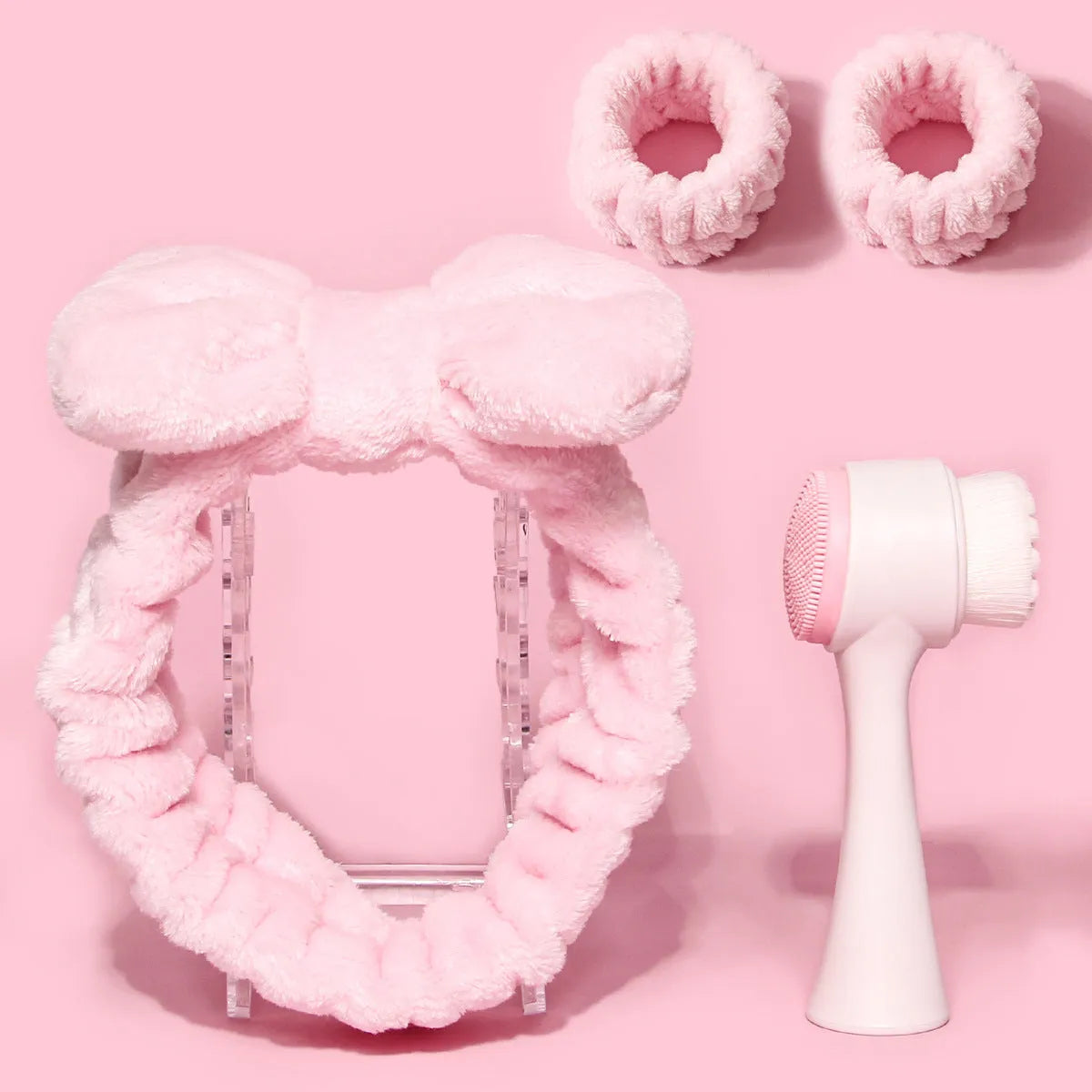 Keep dry facial brush set with plastic handle, coral fleece hair band, and stack of purple and pink face wash sponge suits.