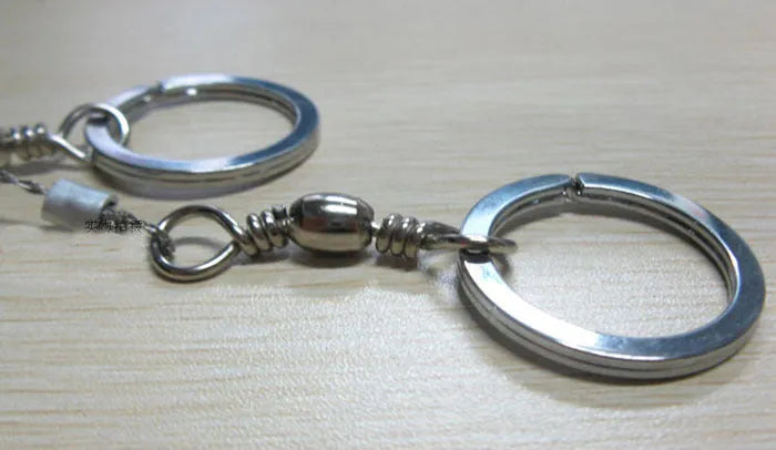 55cm stainless steel survival wire saw with pull rings and hoops on a green background.