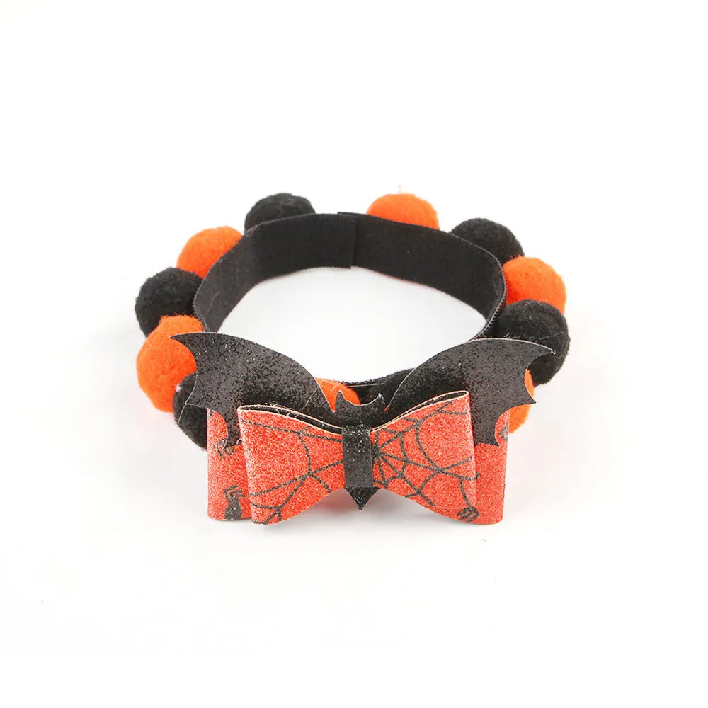 Halloween dog collar with a large orange pom-pom and pumpkin design on an adjustable black band.