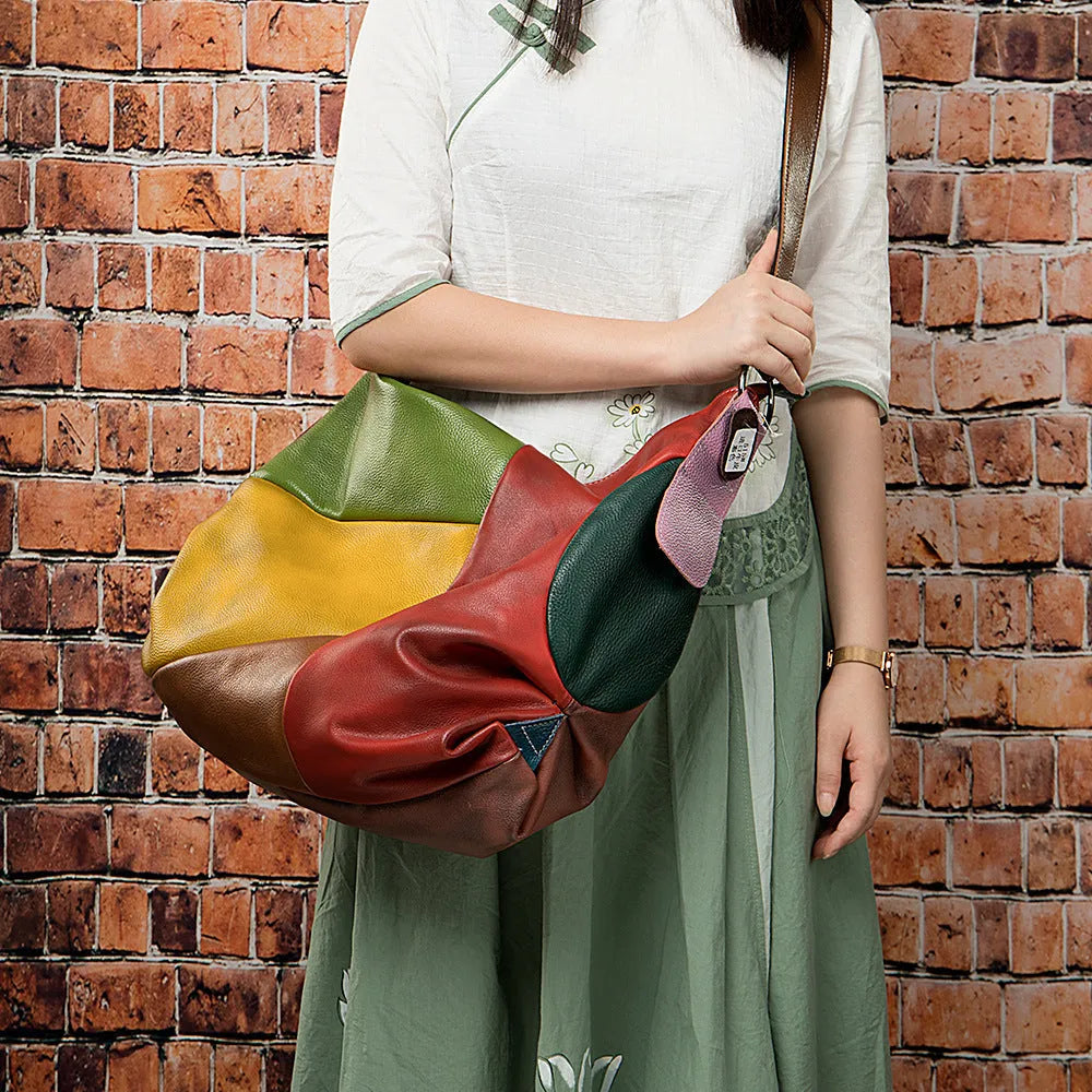 Brown cowhide leather crossbody travel bag with stitching detail, shown holding a laptop and A4 magazine.