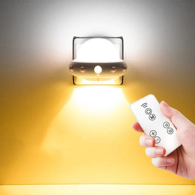 A small blue UFO-shaped bedside night light with a remote control on a wooden table.