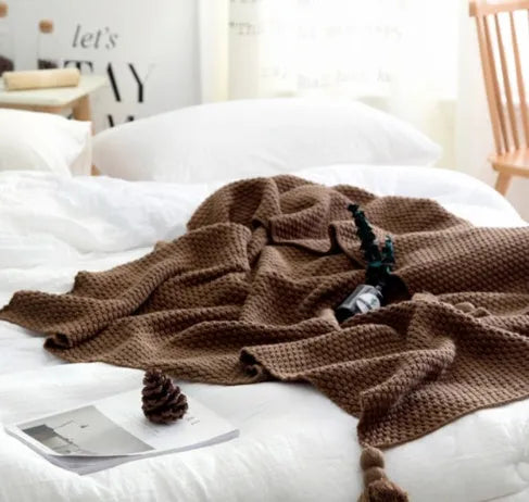 Nordic fringed knit ball acrylic blanket in beige colour on a sofa