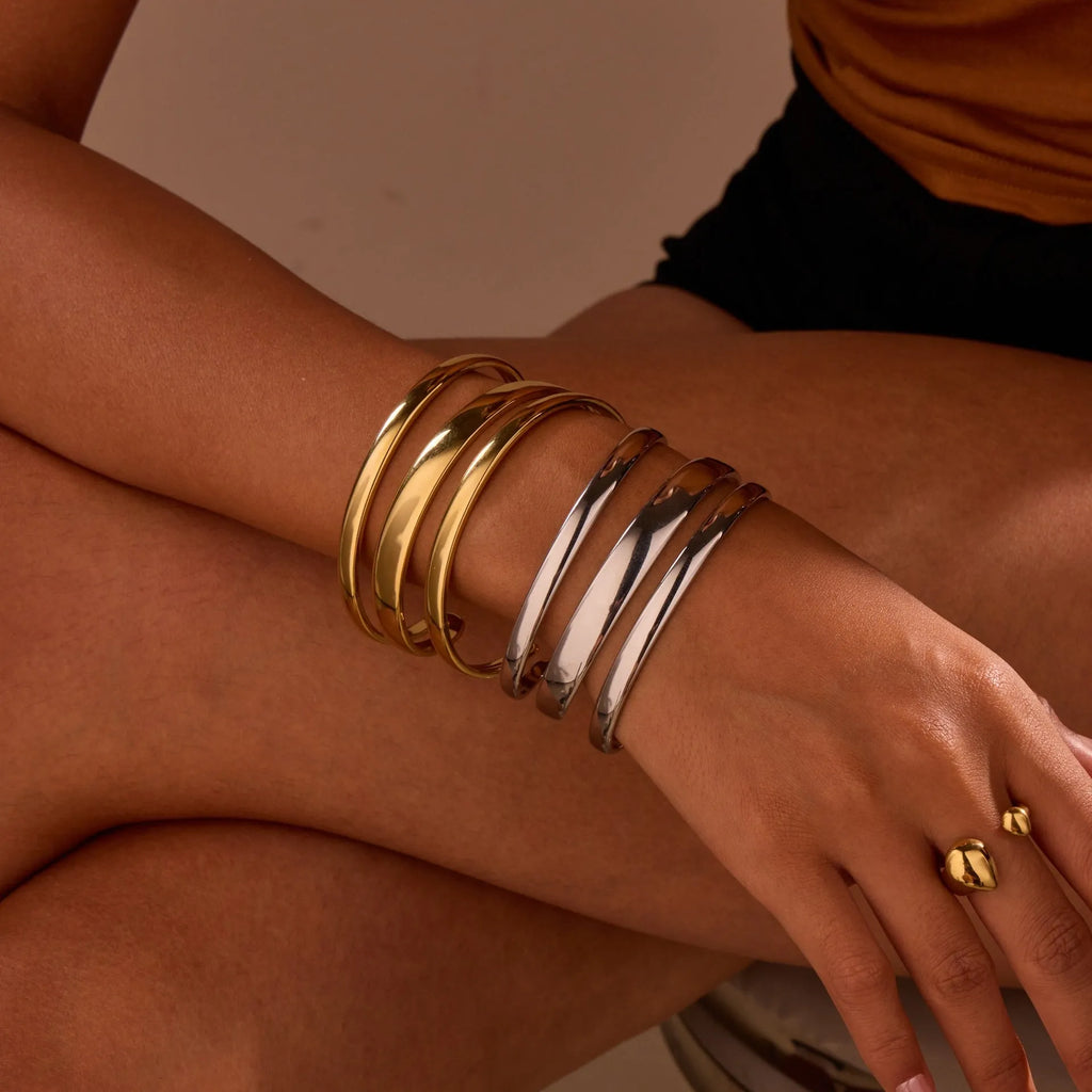 Geometric stainless steel women's bracelet with a simple opening mechanism, shown in gold and steel finish options.