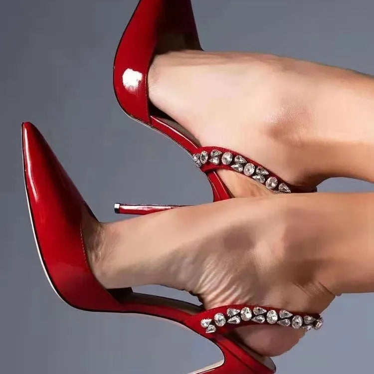 Women's black patent leather pointed toe stiletto sandals with rhinestone decorations along the side.