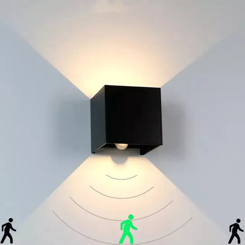 Compact black aluminium cube LED wall lamp mounted on a white wall.