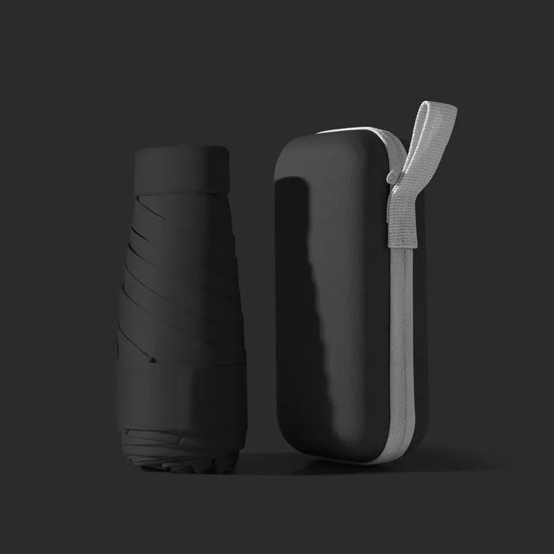 A folded six-fold flat umbrella in a capsule box, showing the steel ribs and rubber handle.