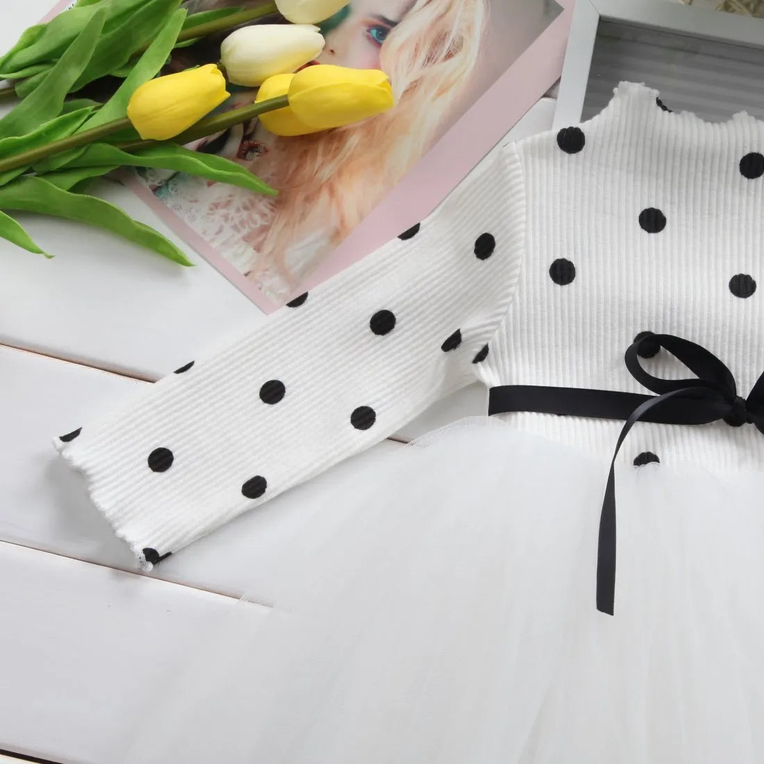 A baby girl wearing a long sleeve black tutu and lace dress for a birthday party.