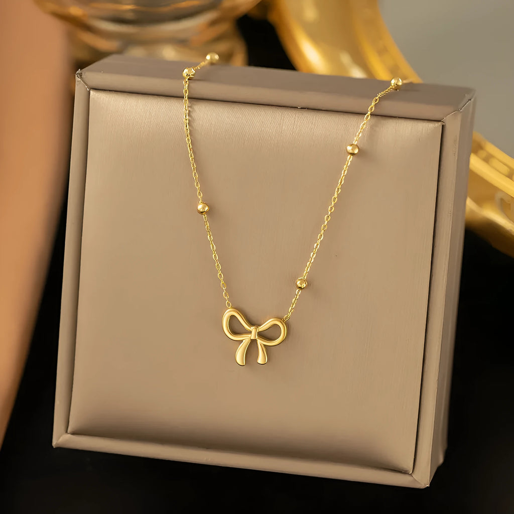 Gold electroplated bow necklace with adjustable chain on white background