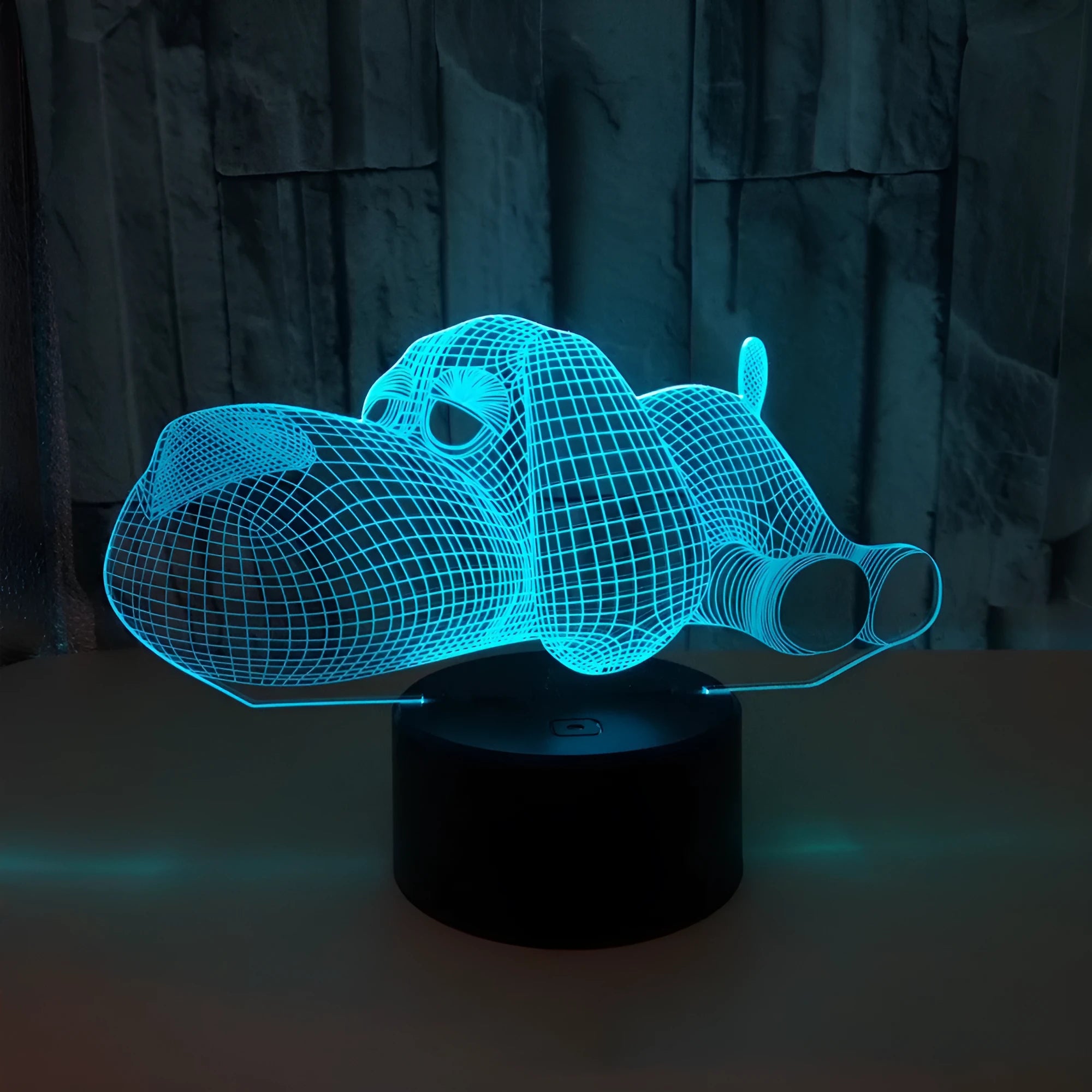 Dog-shaped 3D desktop lamp glowing in multiple colours on a wooden surface.