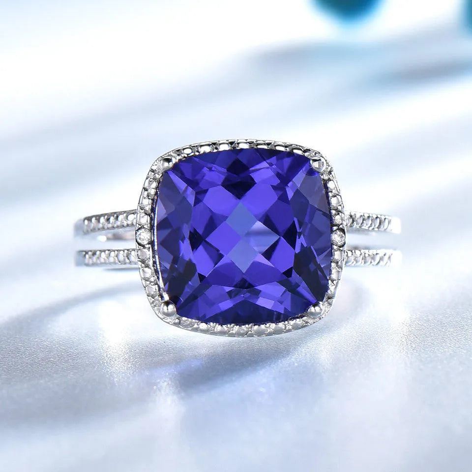 Blue tanzanite stone set in a sterling silver women's ring on a finger.