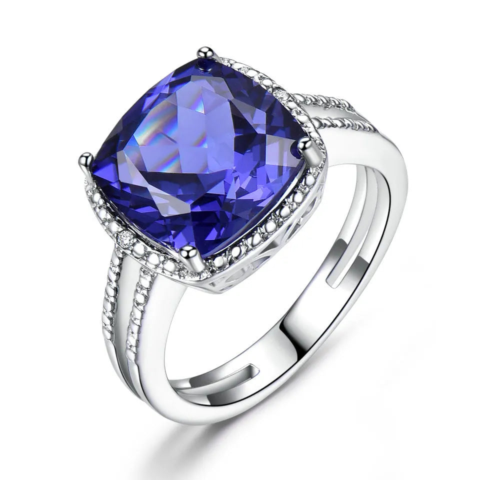 Blue tanzanite stone set in a sterling silver women's ring on a finger.