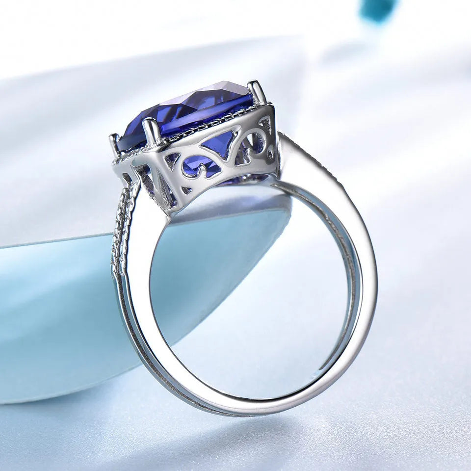 Blue tanzanite stone set in a sterling silver women's ring on a finger.