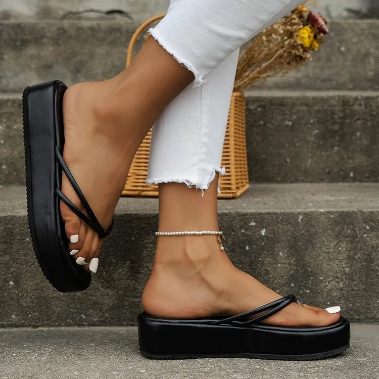 Thick rubber sole flip-flops in multiple colours on a beach background.