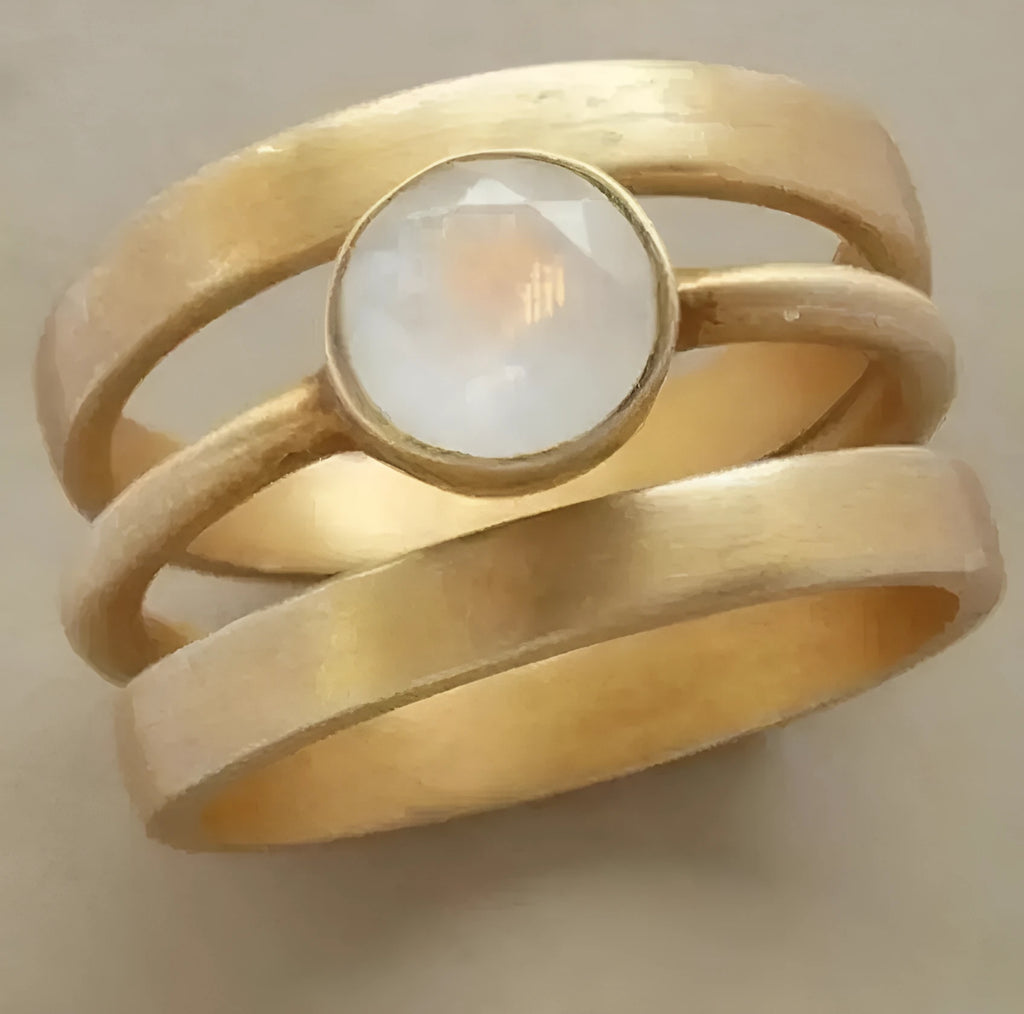Gold geometric titanium steel ring with micro-inlaid white chalcedony stone on a plain background
