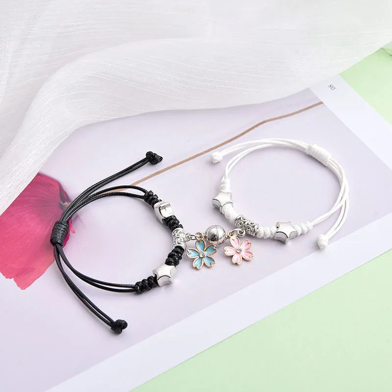 Pair of magnet couple bracelets with suction clasp on wrist, showing alloy designs like crown and love lock.