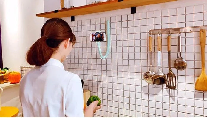 Flexible rubber phone holder with suction cup mounted on desktop showing 360-degree rotation