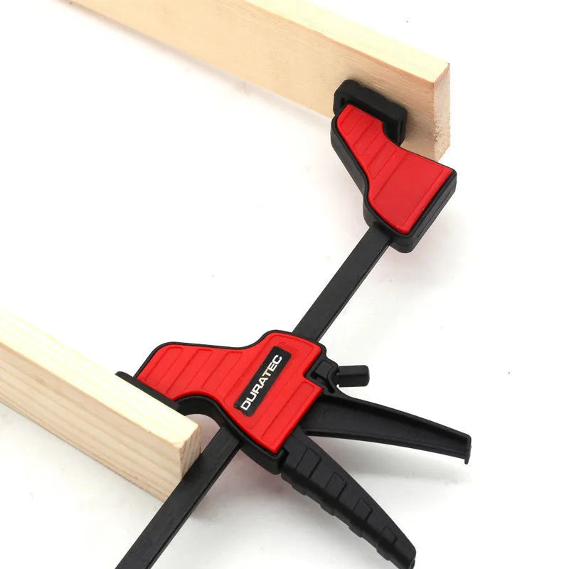 Black plastic woodworking clamp with quick-adjust key and soft rubber protective jaws.