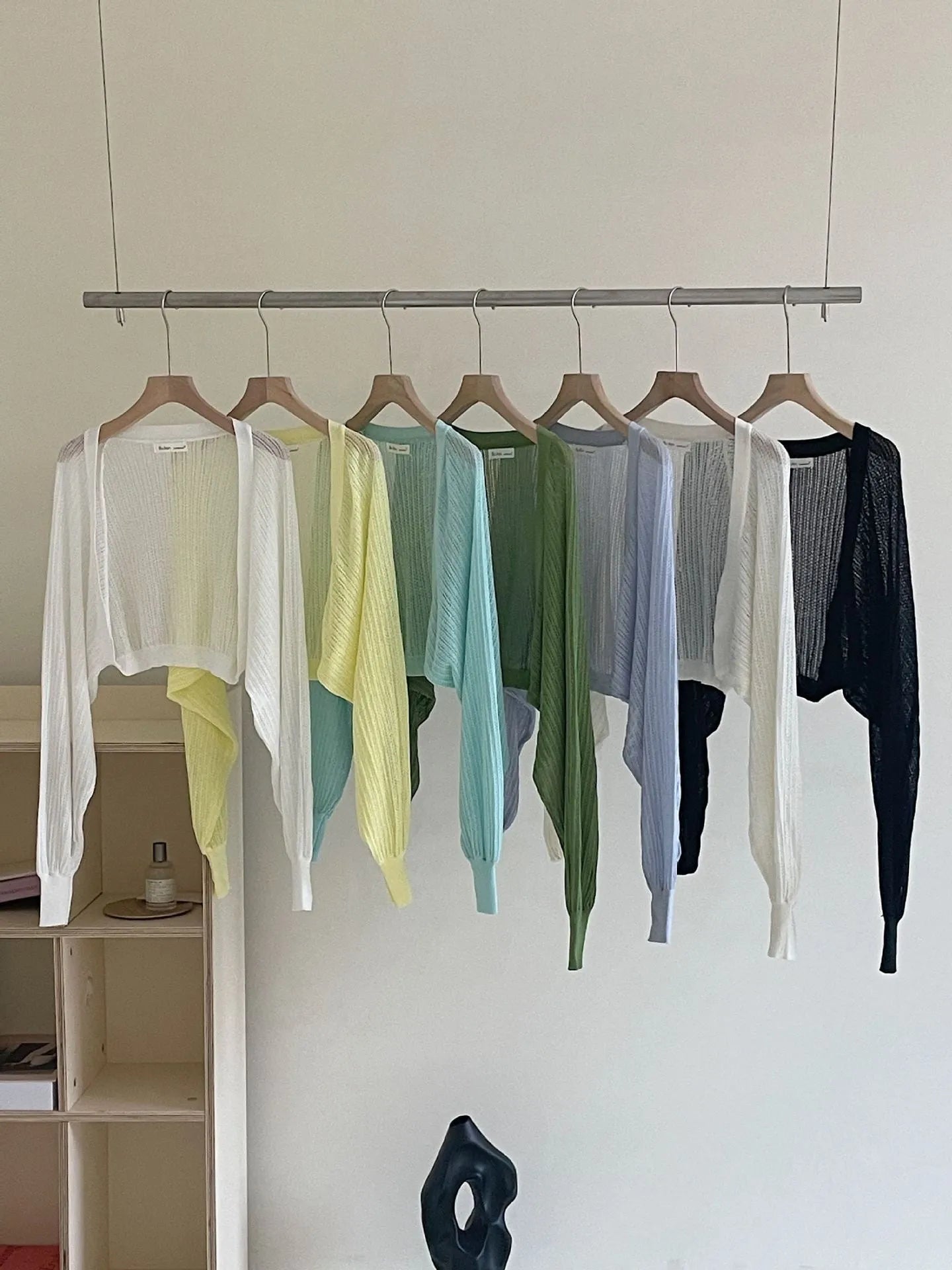 Thin loose linen blouse with hollow out lantern sleeves in apricot colour on a hanger.