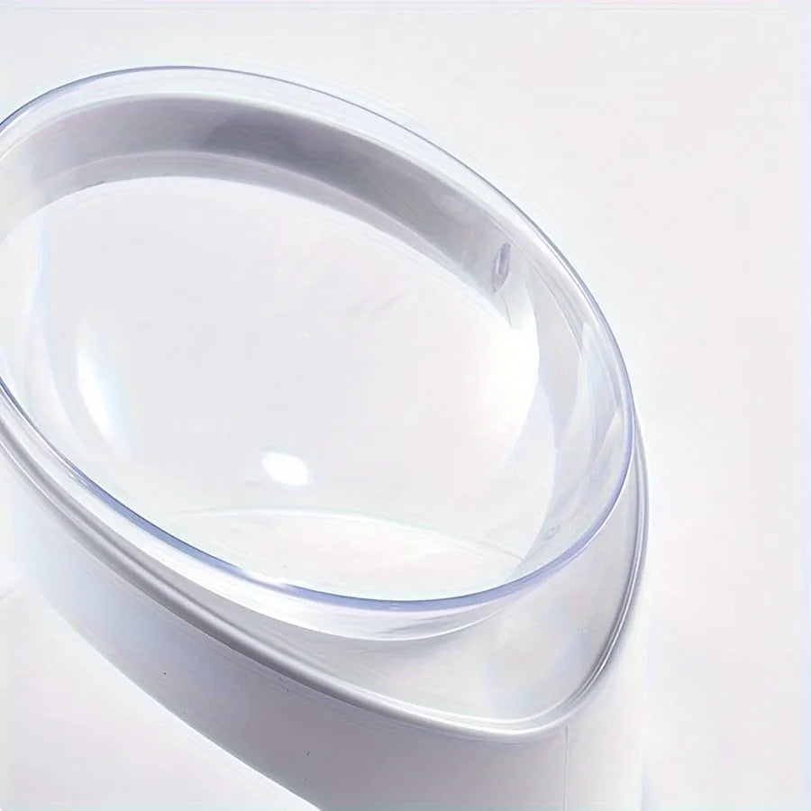 Clear plastic tilted cat food bowl on a flat surface