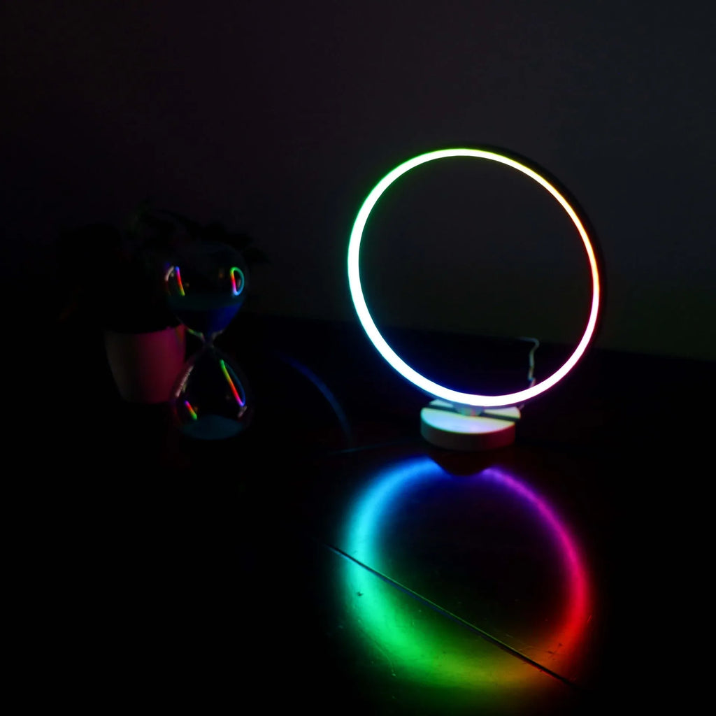White Full Moon shaped table lamp with LED lighting and a remote control on a table.